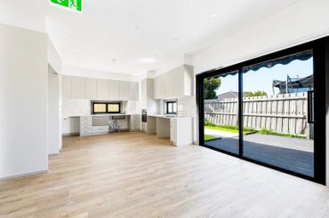 Bright, empty modern kitchen with large sliding glass doors to backyard.