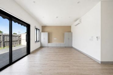 Empty modern room with large sliding glass doors and wooden flooring.