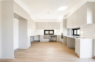 Bright, modern kitchen with light wood flooring and white cabinetry.