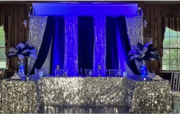 Elegant event table with shimmering silver and blue decor and floral centerpieces.