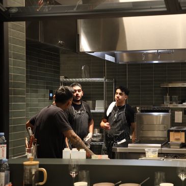 Three chefs in a professional kitchen talking.