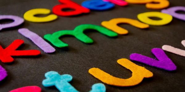 Colorful felt alphabet letters arranged on a dark surface.