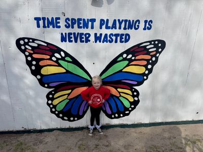 Child with butterfly wings mural and motivational quote.