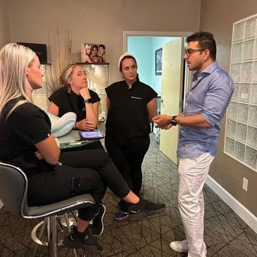 A man in blue shirt discusses with three women in a casual office setting.