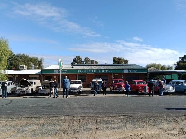 Vintage cars parked in front of Post Office Hotel with people around.