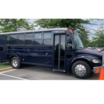 A dark blue bus parked in a lot with orange cones nearby.