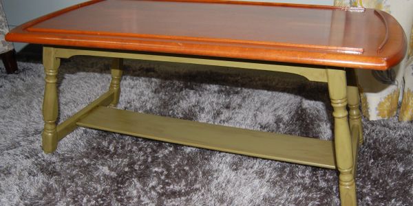 Wooden coffee table with orange top and green legs on a shaggy carpet.