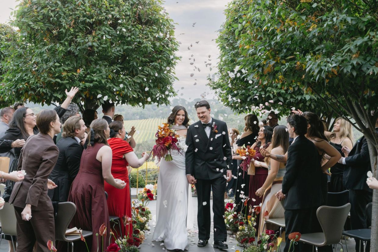 Bride and groom walking down the aisle with guests throwing flower petals.