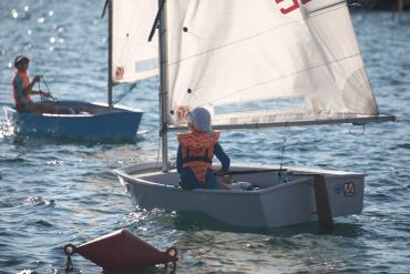 Two young sailors in small sailboats on a sunny day.
