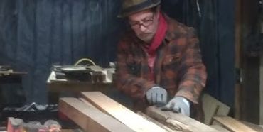 
the owner at a table saw ripping down 140 year old heart pine studs into thin strips to make panels