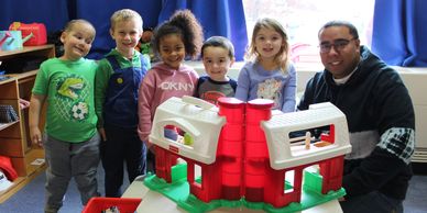 Teacher and five students in Pre-School Room.