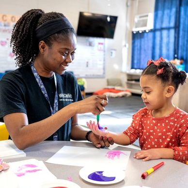 Pre-School teacher doing painting activity with student.