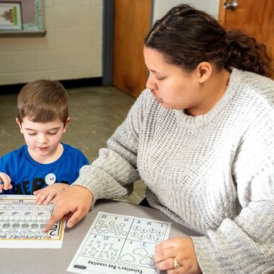 Pre-K teacher helping student with classwork.