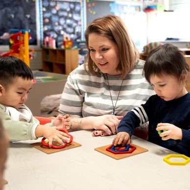 Toddler teacher overseeing table activity.