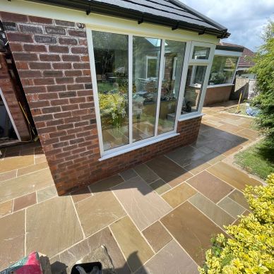 Newly installed stone patio surrounding a brick house extension.