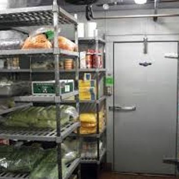 Organized storage shelves inside a walk-in refrigeration unit.