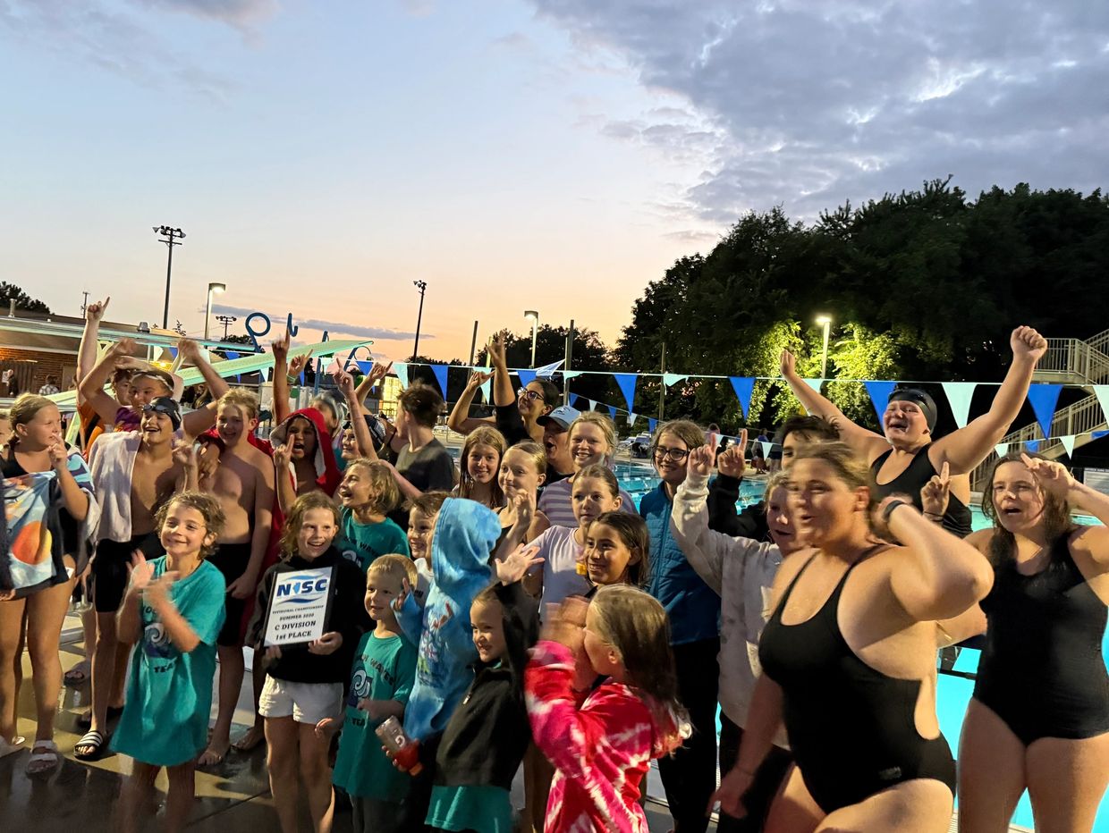 Children celebrating a swimming competition win at sunset.