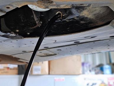 Engine oil being drained from a vehicle during a routine service at a professional workshop