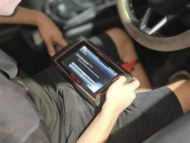 Mechanic using a diagnostic scanner to check vehicle warning light faults.
