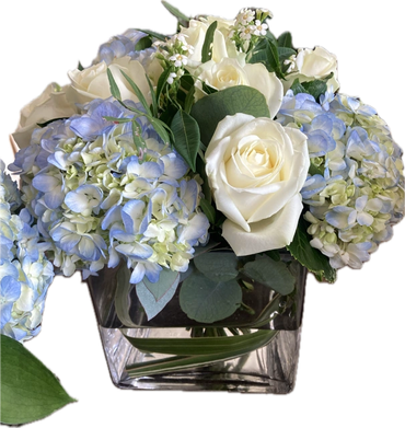 White roses and blue hydrangeas in a glass vase.