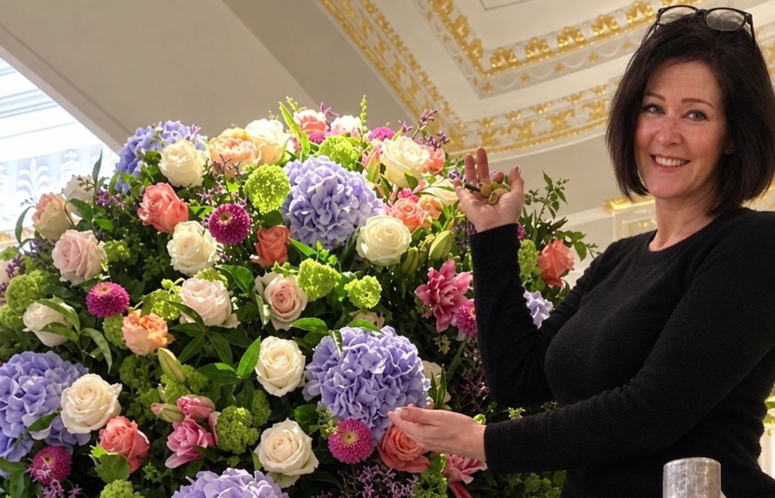 Woman smiling next to a large bouquet of colorful flowers.