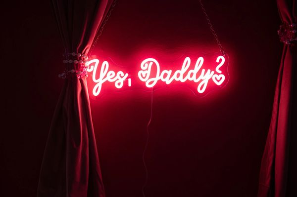 Yes, Daddy neon sign in the Brat kink room