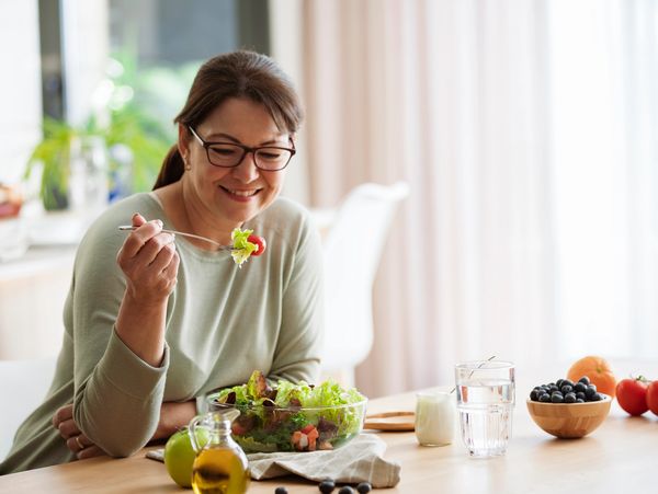 Woman eating freshly prepared lettuce salad at home. Healhy eating and dieting concept