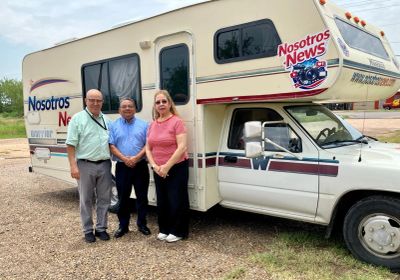 Tres personas frente a una camioneta con un logo de "Nosotros News".