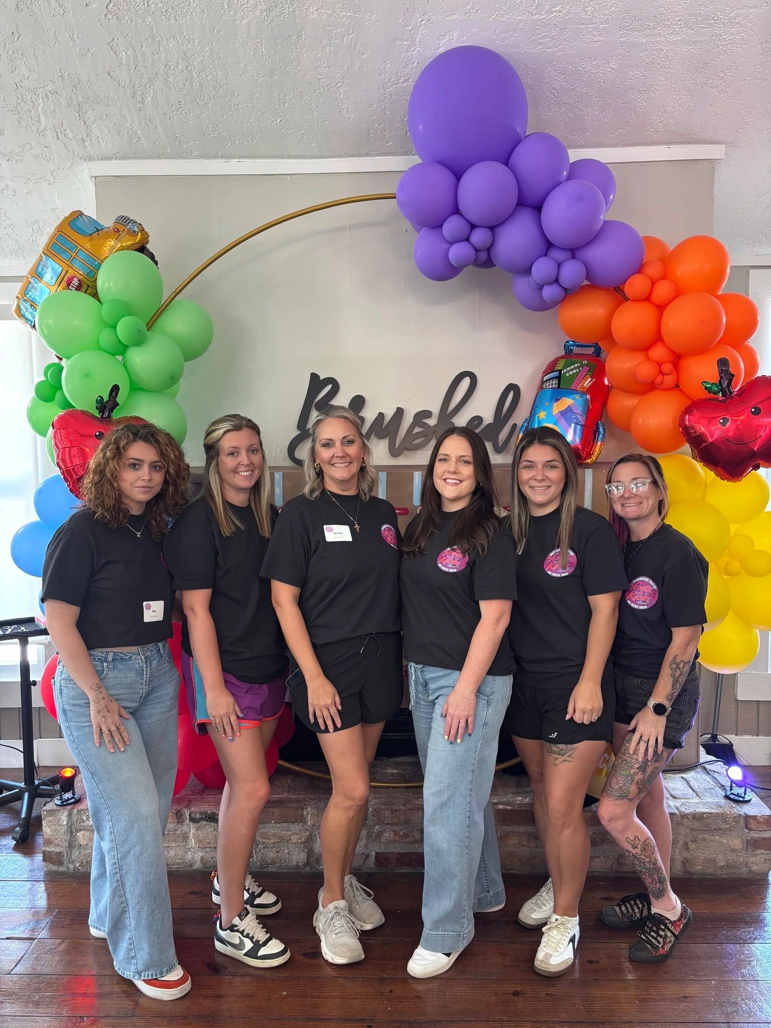 Group of six women posing with colorful balloons.