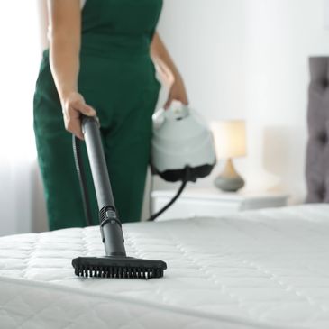 A professional vacuuming a bed