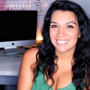 Smiling woman with long dark hair in front of a computer.