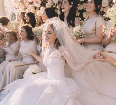 Bride and bridesmaids joyfully holding hands at a wedding.