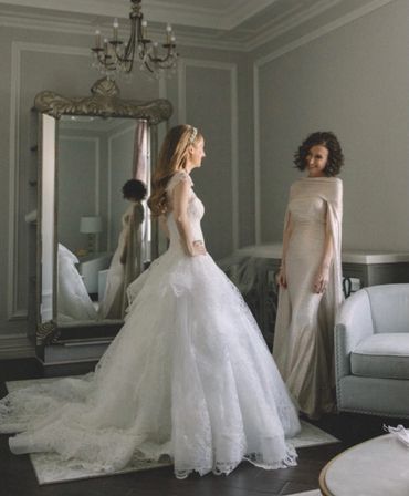 Bride in a white gown and a woman in an elegant dress in a stylish room.