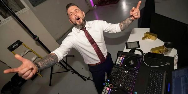 Energetic DJ in a white shirt and tie performing with equipment.