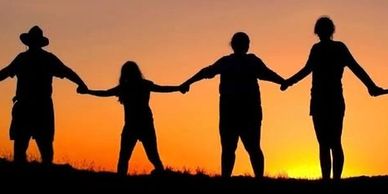 Silhouettes of people holding hands during a sunset.