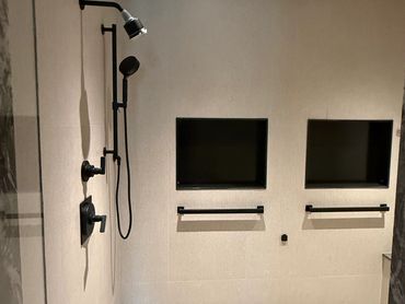 Modern shower area with dual TVs embedded in the wall.