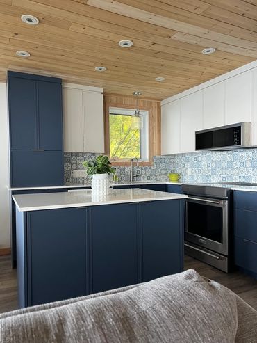 Modern kitchen with navy blue cabinets, white countertops, and patterned tile backsplash.