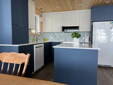 Modern kitchen with blue cabinets, white countertops, and wooden ceiling.