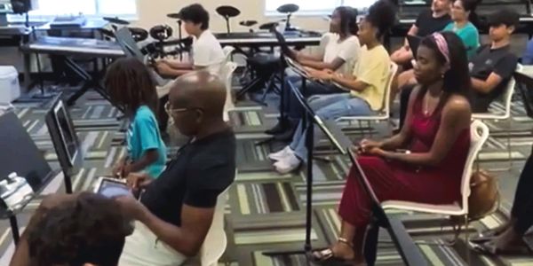 A diverse group attending a music class with electronic instruments.