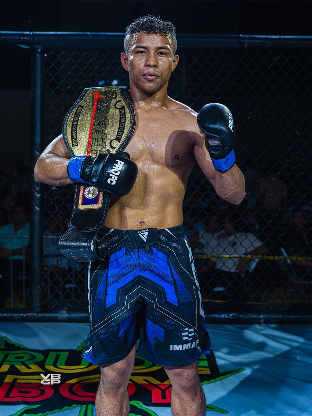 MMA fighter proudly holding a championship belt inside an octagon cage.