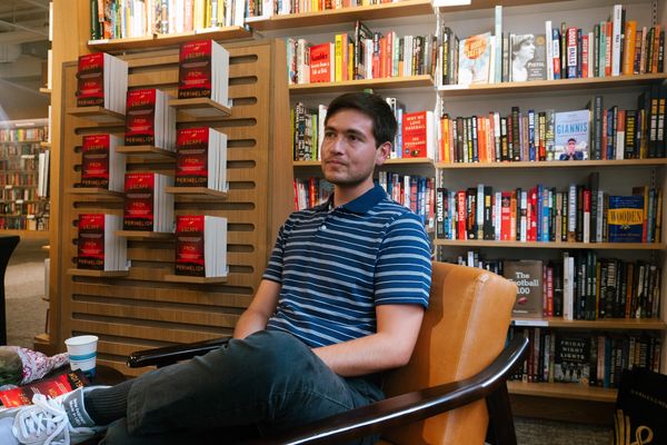 Man sitting in a bookstore with books behind him.