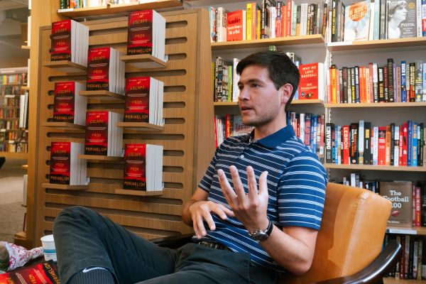 Man in striped shirt talking in a bookstore.