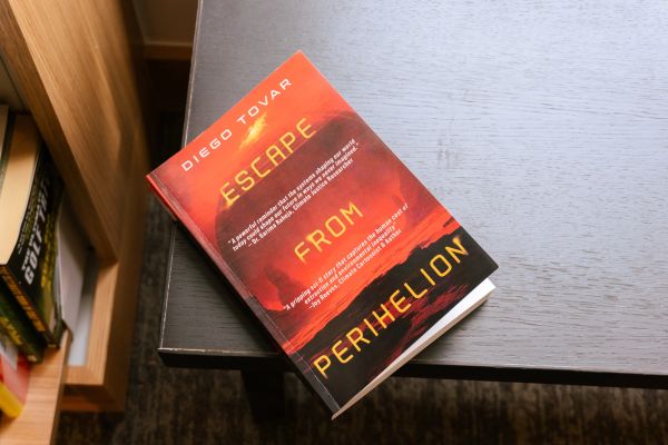 Book titled Escape from Perihelion by Diego Tovar on a desk.