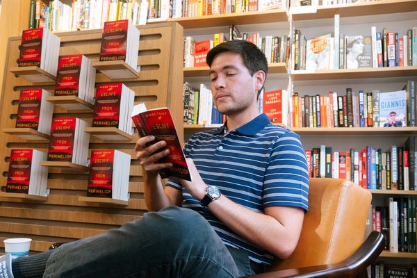 Man reading a book in a bookstore.