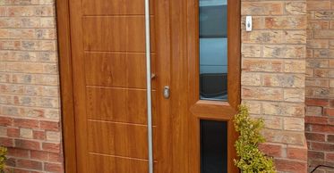 Golden Oak Solid Core composite door with a long bar handle fitted by Mansfield Front Doors.
