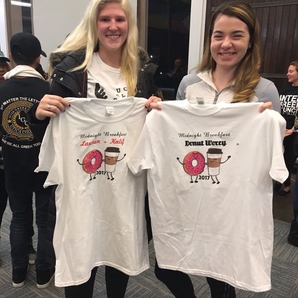 Two people holding their customized shirt