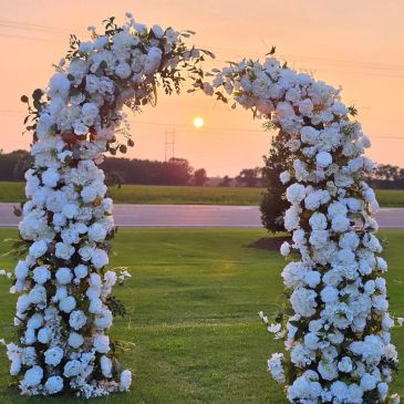 Floral arch with white flowers at sunset.