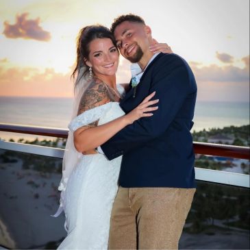 Newlyweds embracing at sunset on a balcony.