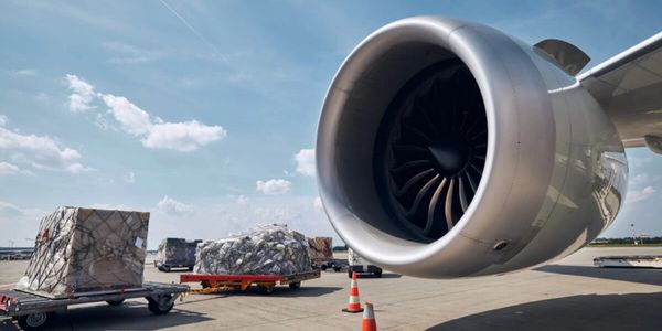 Cargo being loaded near an airplane engine at the airport.