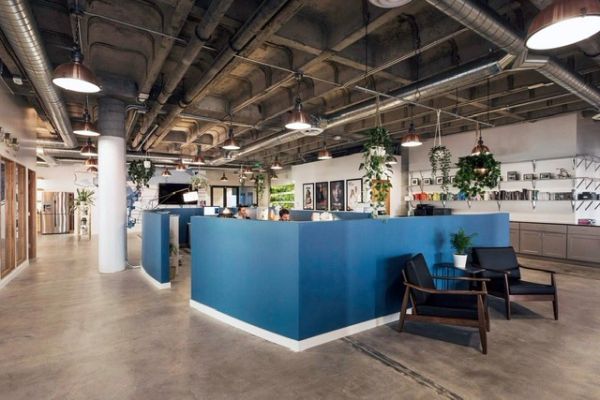 Modern open office with blue cubicles and industrial ceiling.